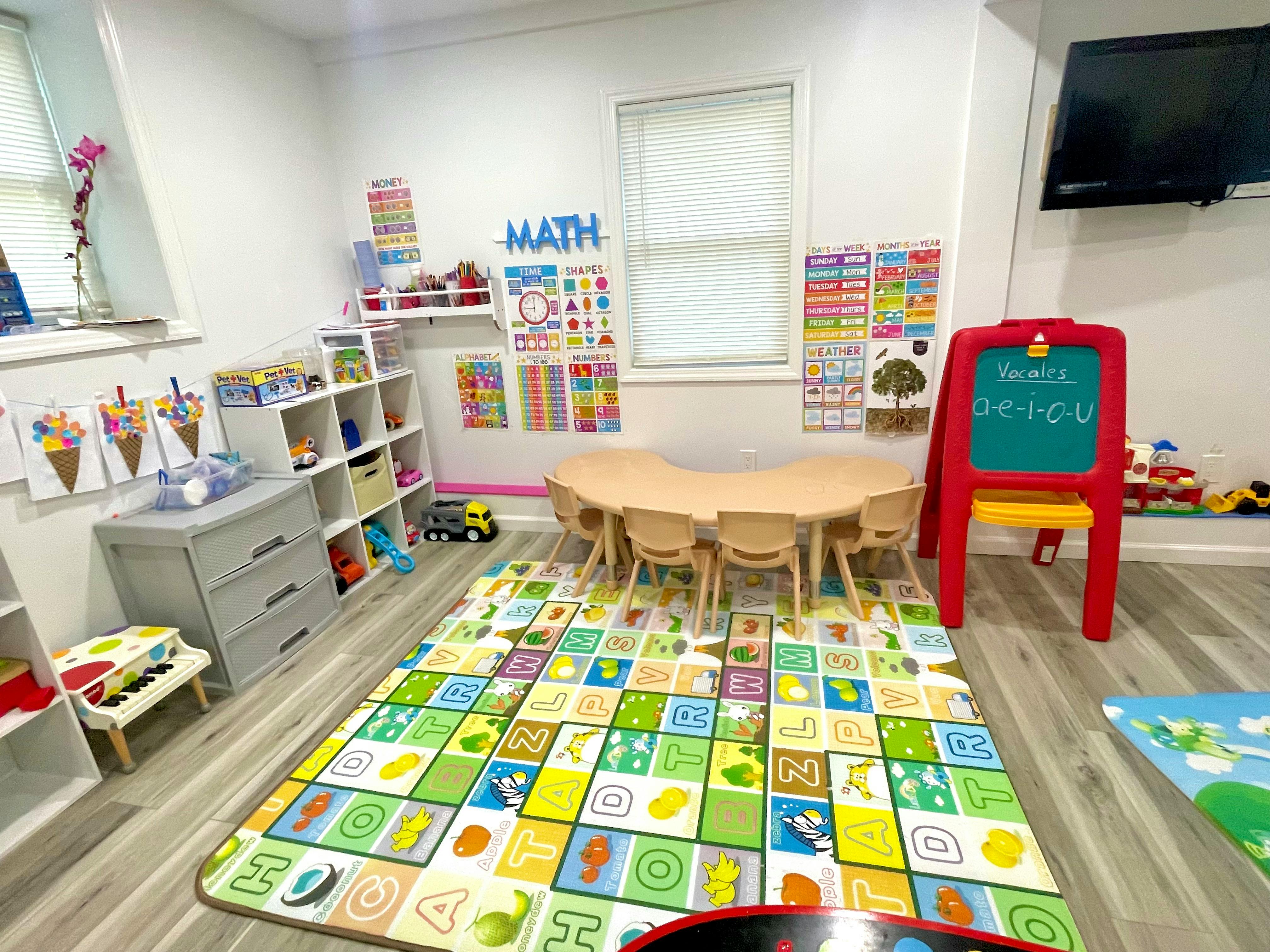 Classroom interior with alphabet floor mat, small table, chairs, and learning aids