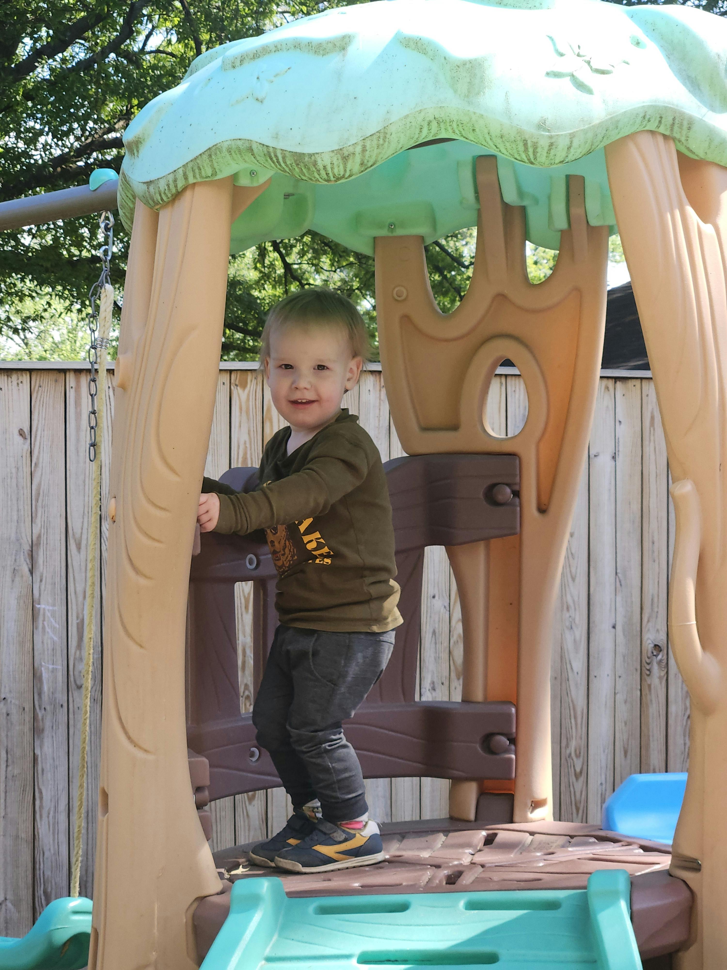 Child standing inside a plastic playground structure