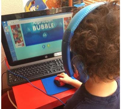 Child with headphones using a computer mouse
