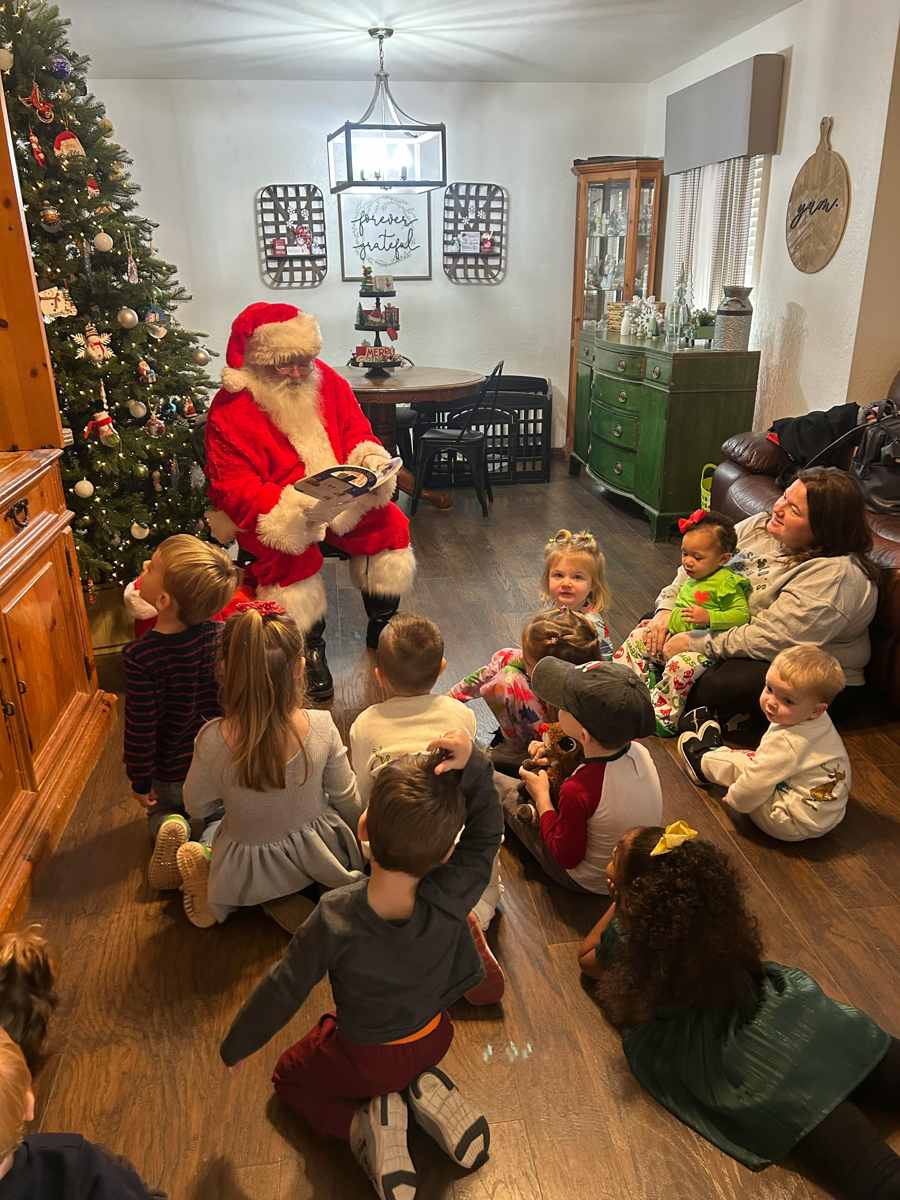 Person dressed as Santa Claus reading to a group of children