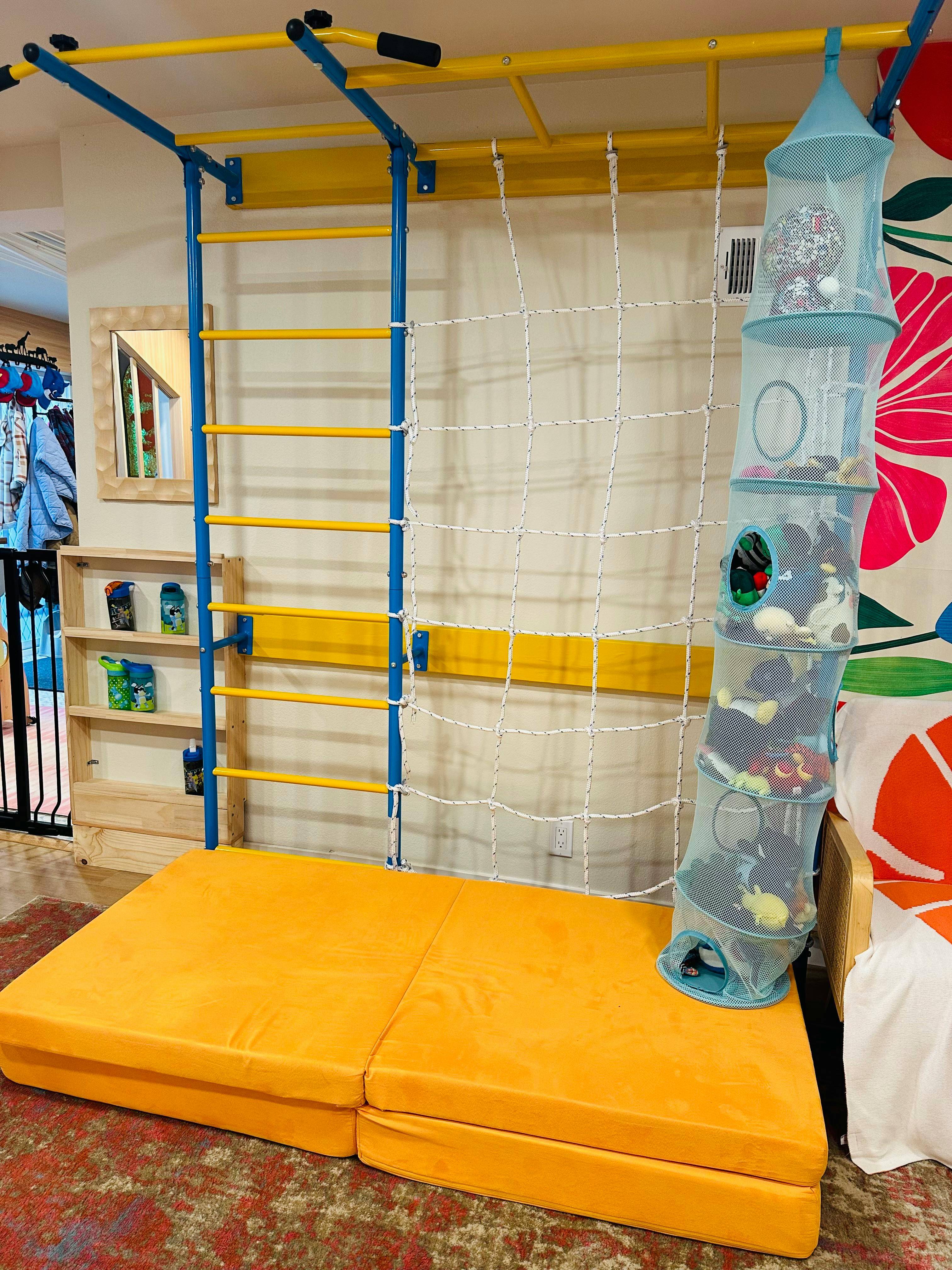 Indoor climbing structure with ladder, net, and soft mat
