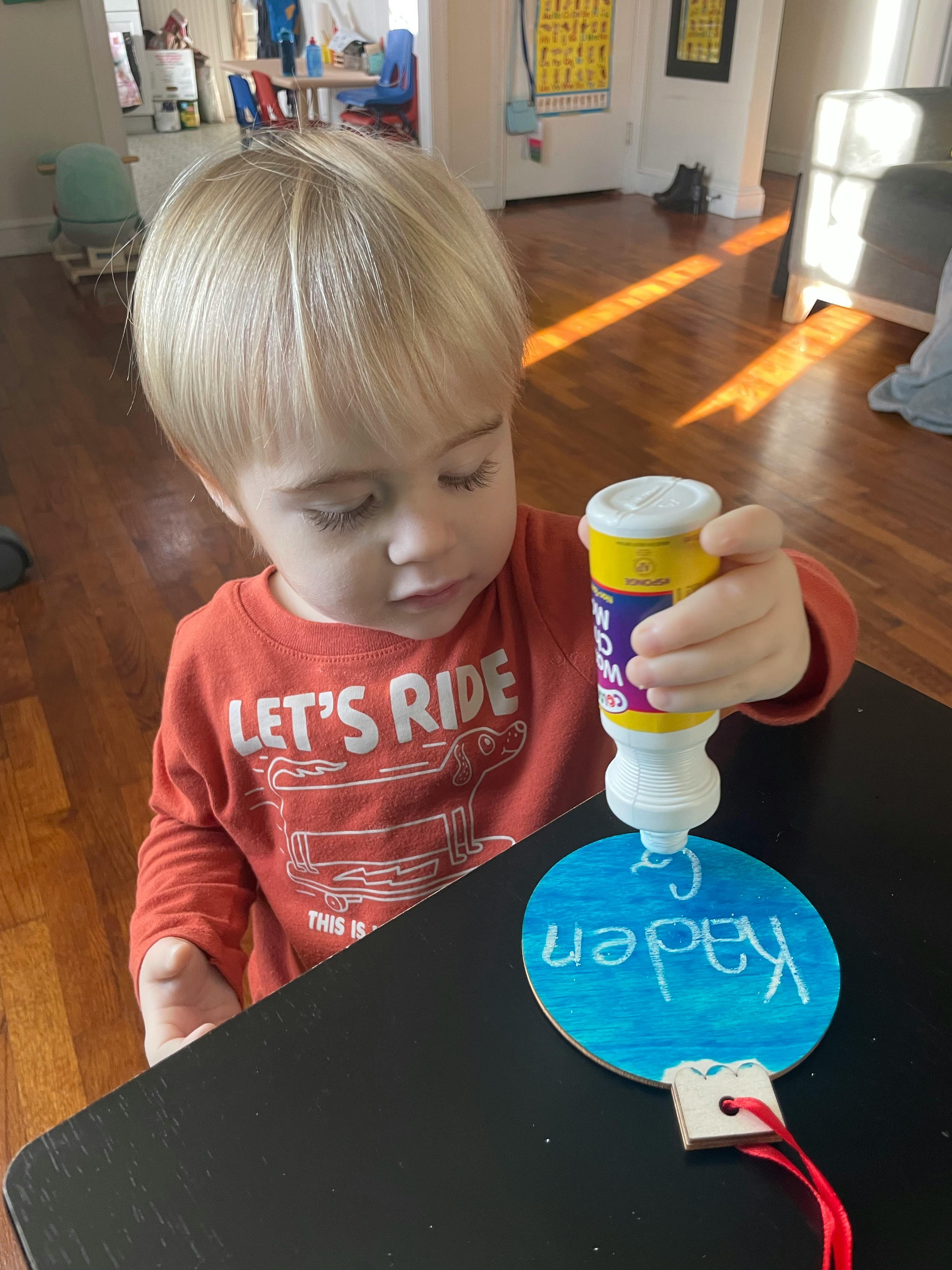 Child applying glue to a blue circular craft