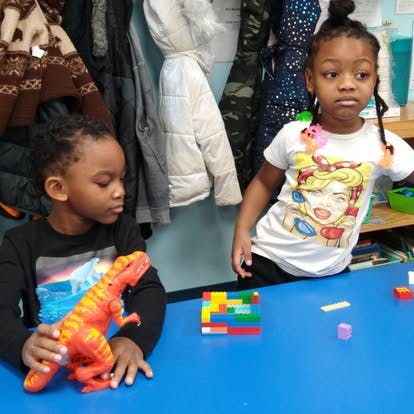 Two children playing with toys at a table