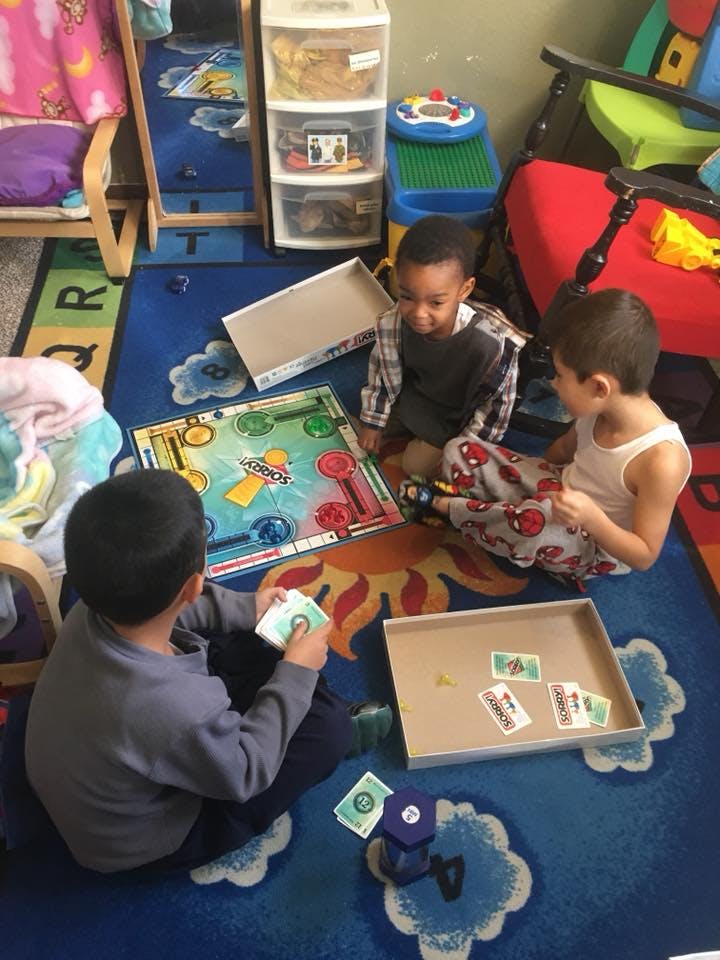 Three children playing a board game on a rug