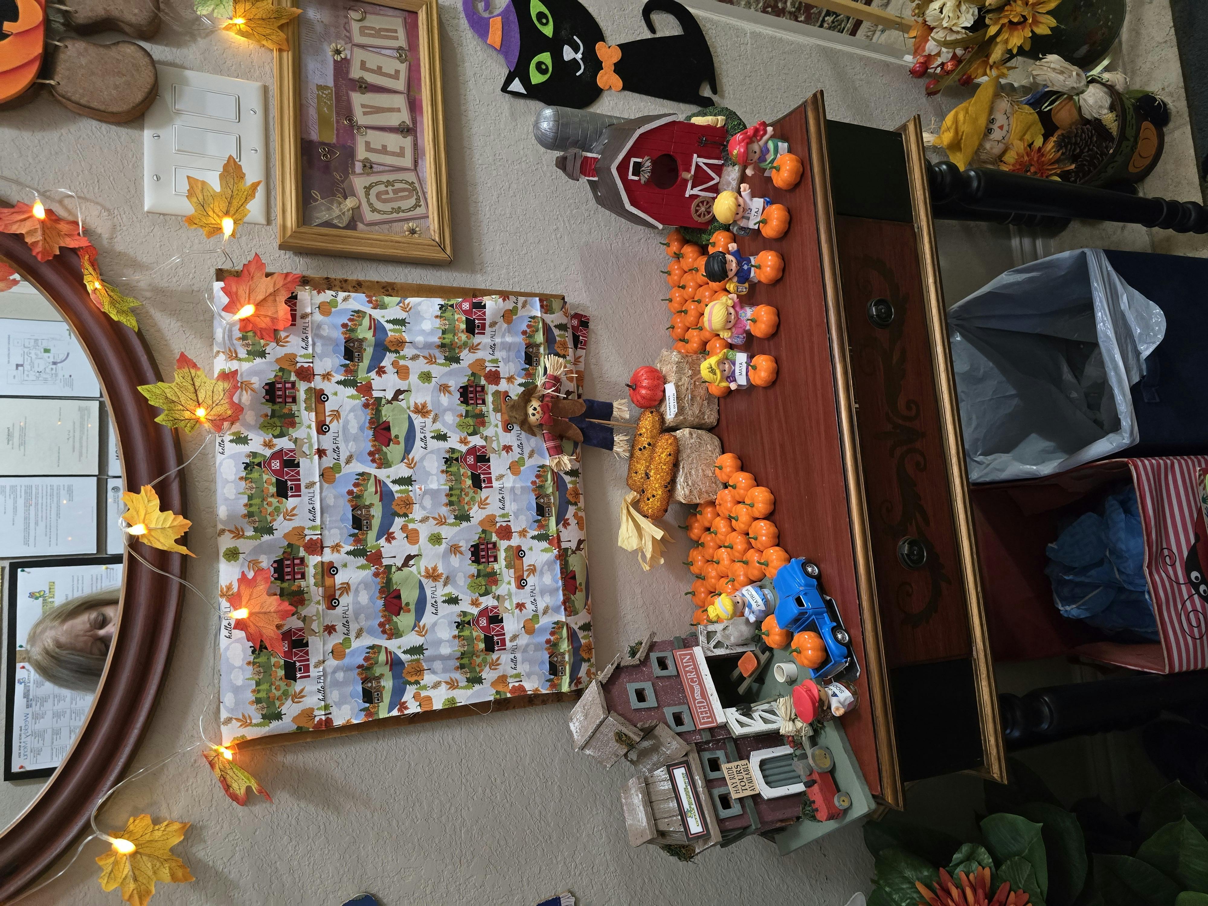 Wall decorated with fall-themed items, including a quilt and figurines