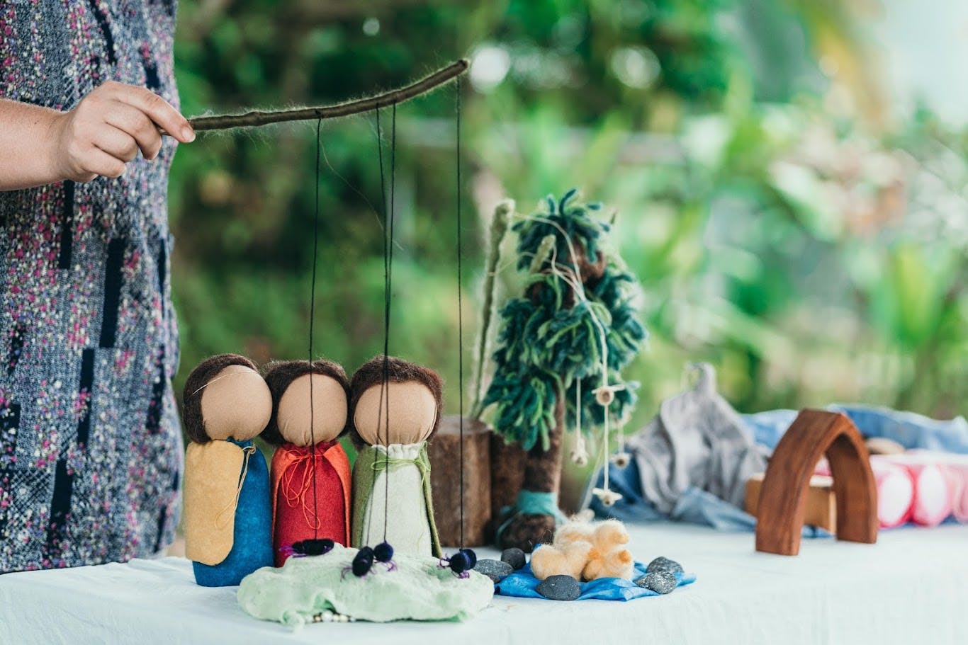 Person holding a stick puppet with three figures over-sized dolls