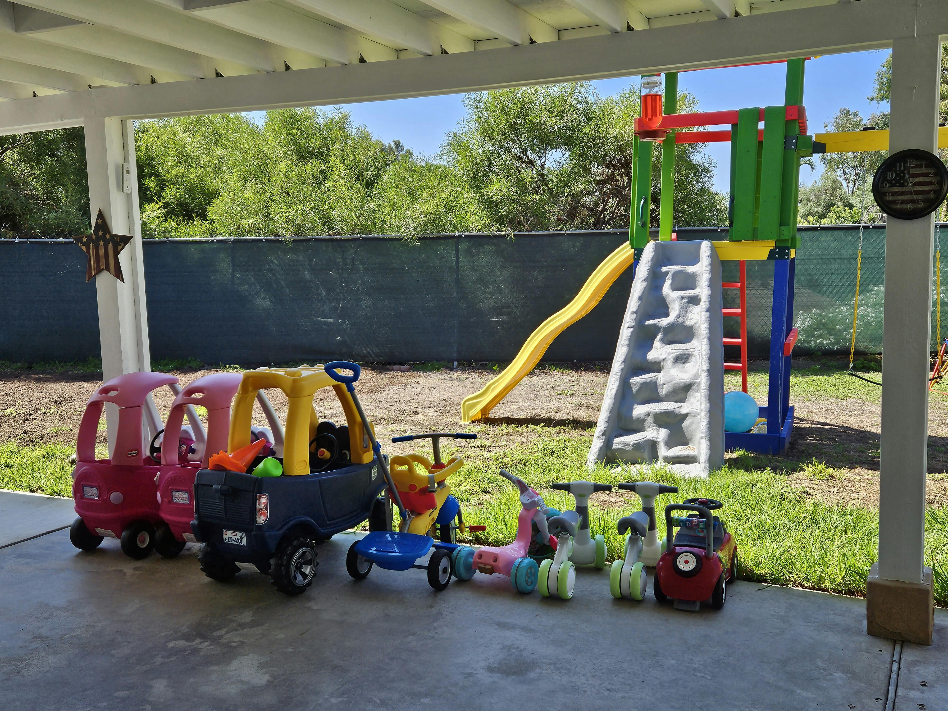 Children's ride-on toys and a colorful playground set with a slide
