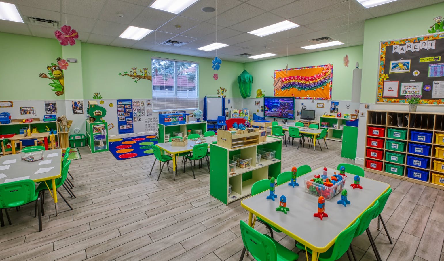 Colorful classroom with small tables and chairs, toys, and educational decorations