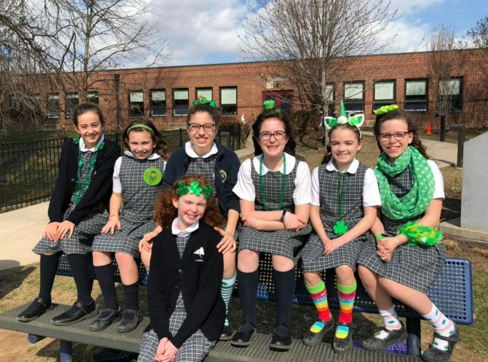 Group of children and teens in uniform sitting outdoors