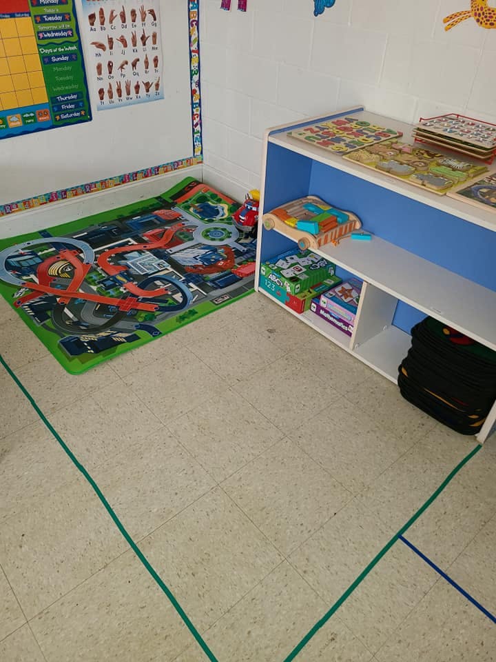 Playroom with a toy car rug and a shelf of puzzles and puzzles