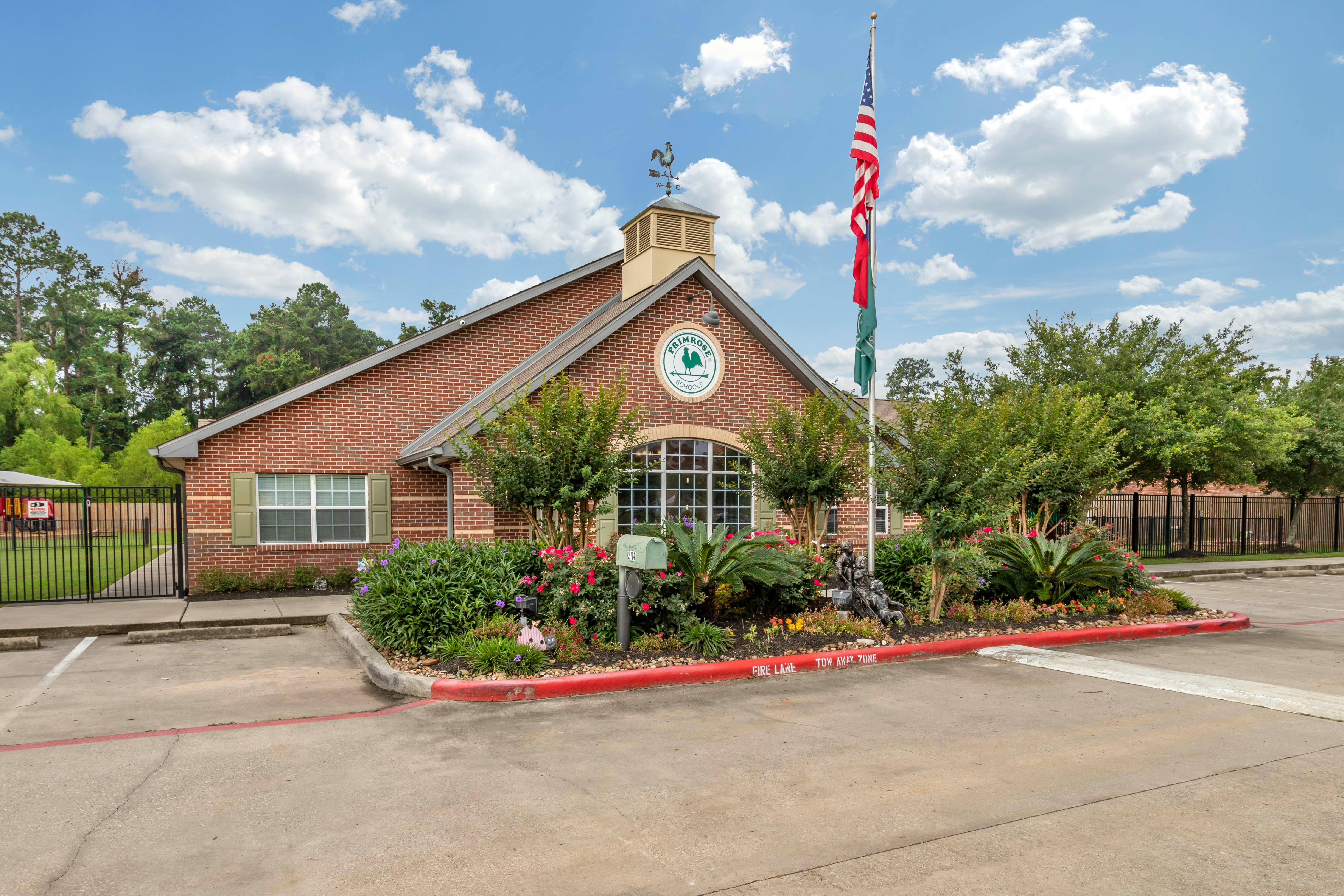 Brick building with a circular sign displaying "Primrose Schools" and a rooster weather vane