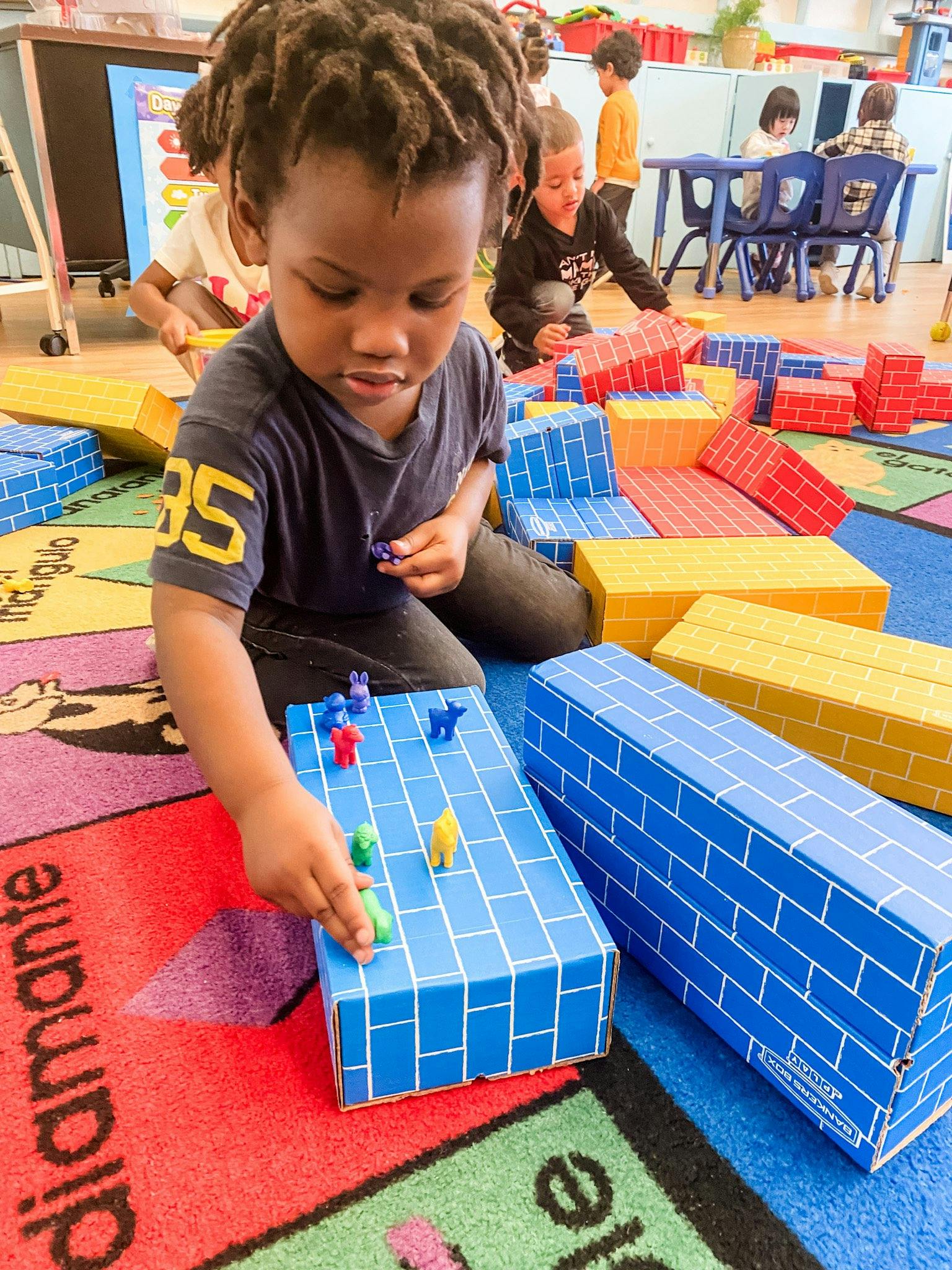 Child playing with small animal figures on a blue block