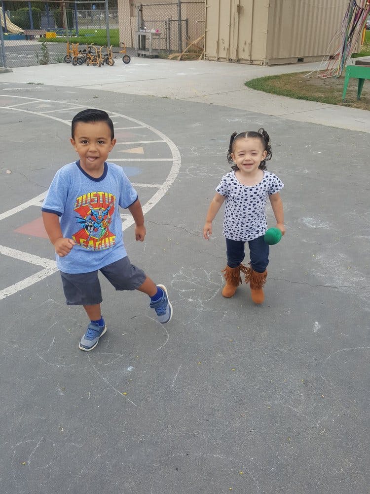 Two children standing on a paved surface