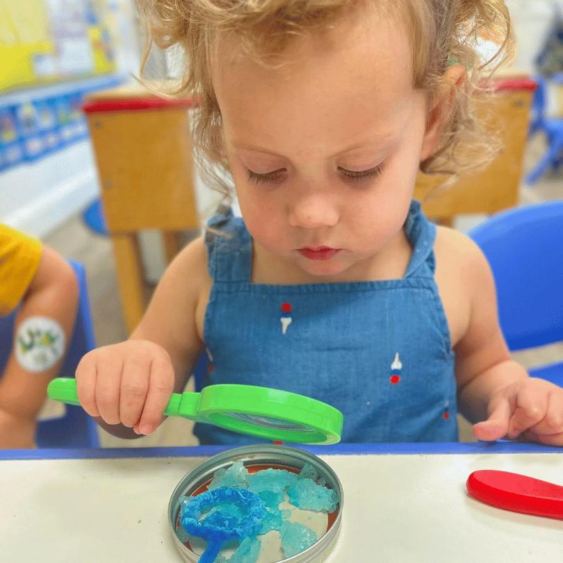 Child examining blue crystals with a magnifying glass
