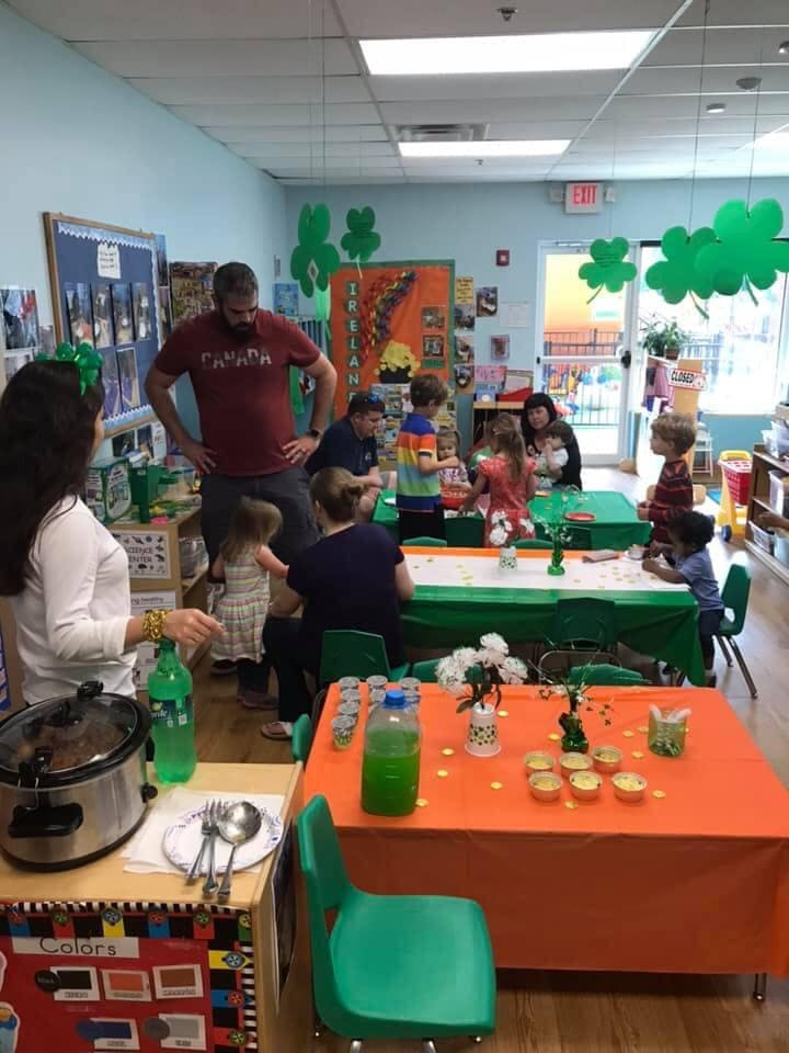 Adults and children gathered around tables in a classroom