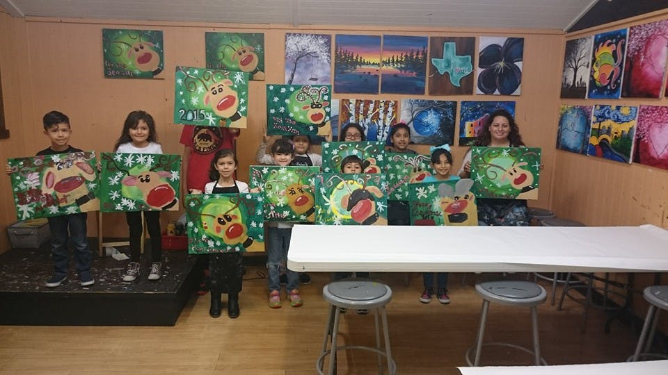 Group of children and adults holding up paintings in-progress paintings