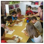 Adult and children seated at a table in a classroom