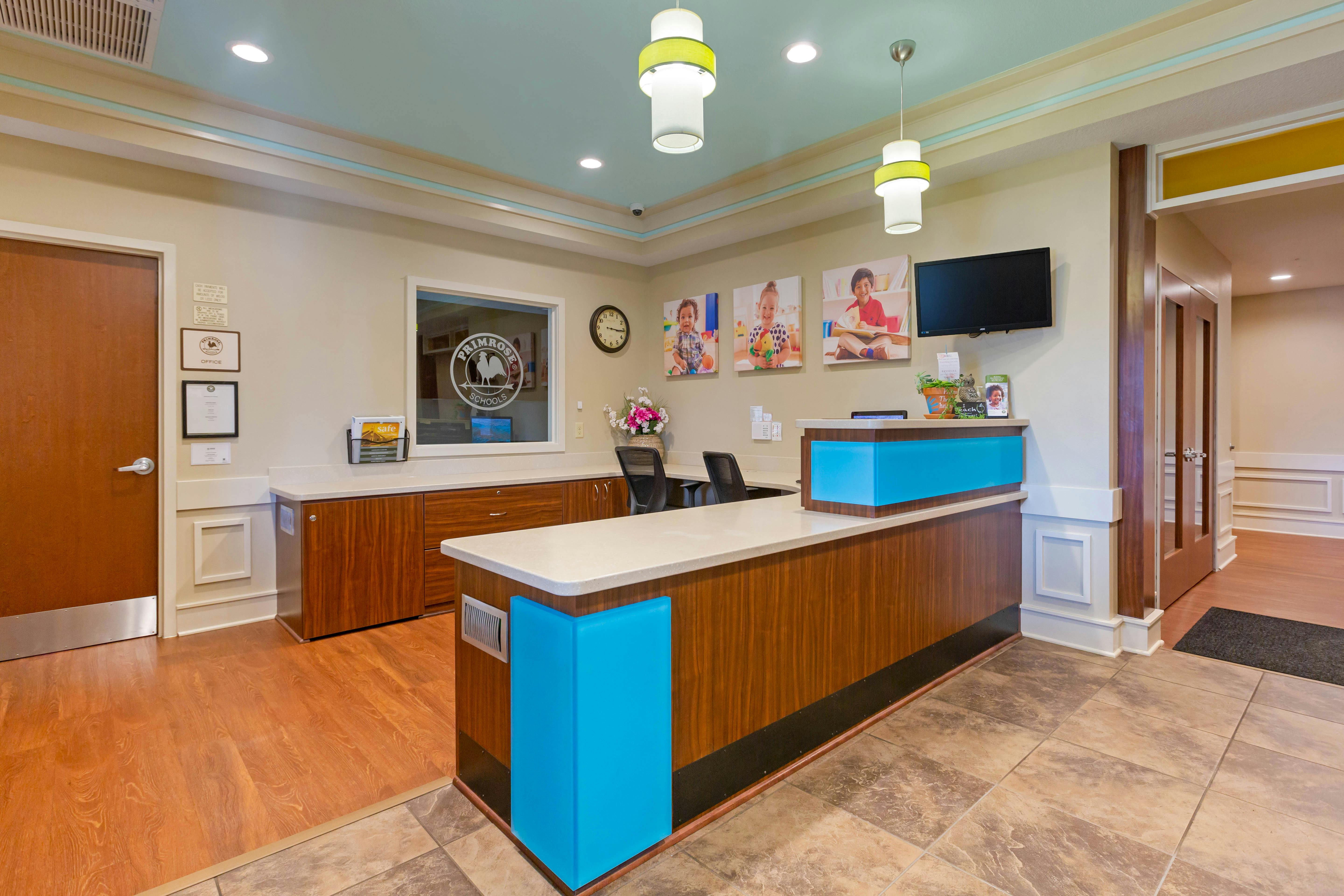 Reception area with a desk, chairs, and large framed photos of children on the wall