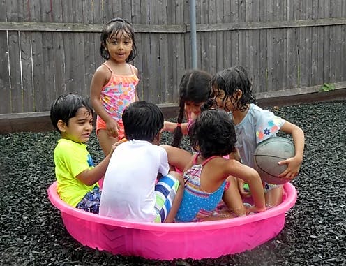 Children playing in a pink plastic pool