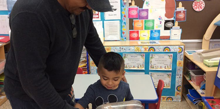 Person standing over a child seated at a small table