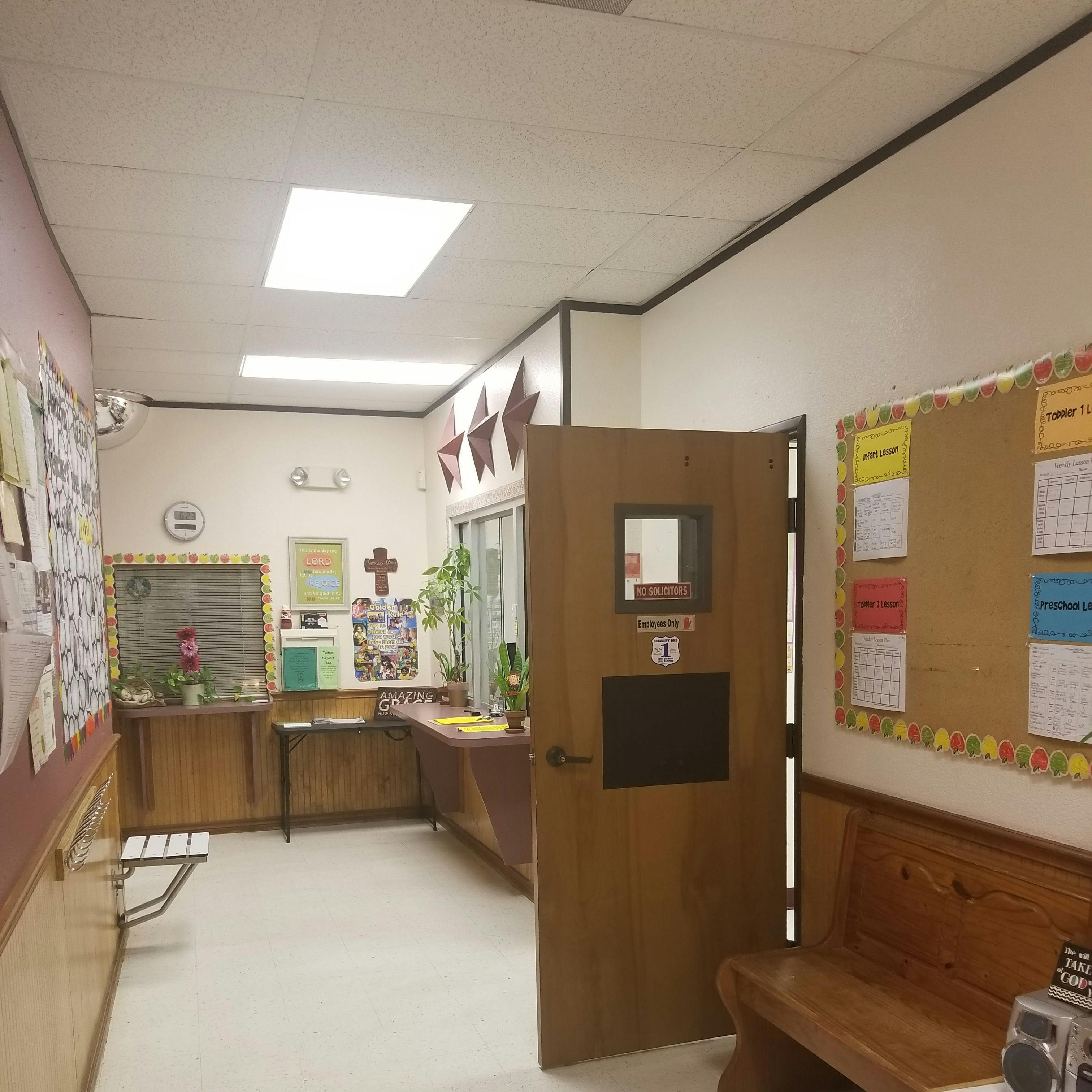 Hallway with a wooden door, bulletin boards, and a wooden bench