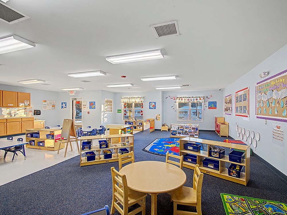 Empty colorful classroom with small tables, chairs, and shelves