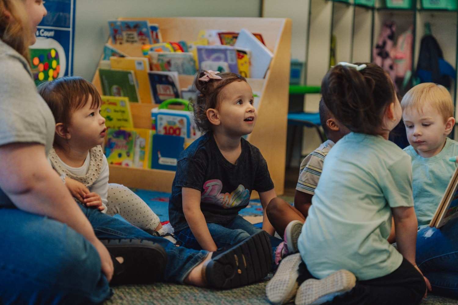 adults and children sitting on the floor in a classroom