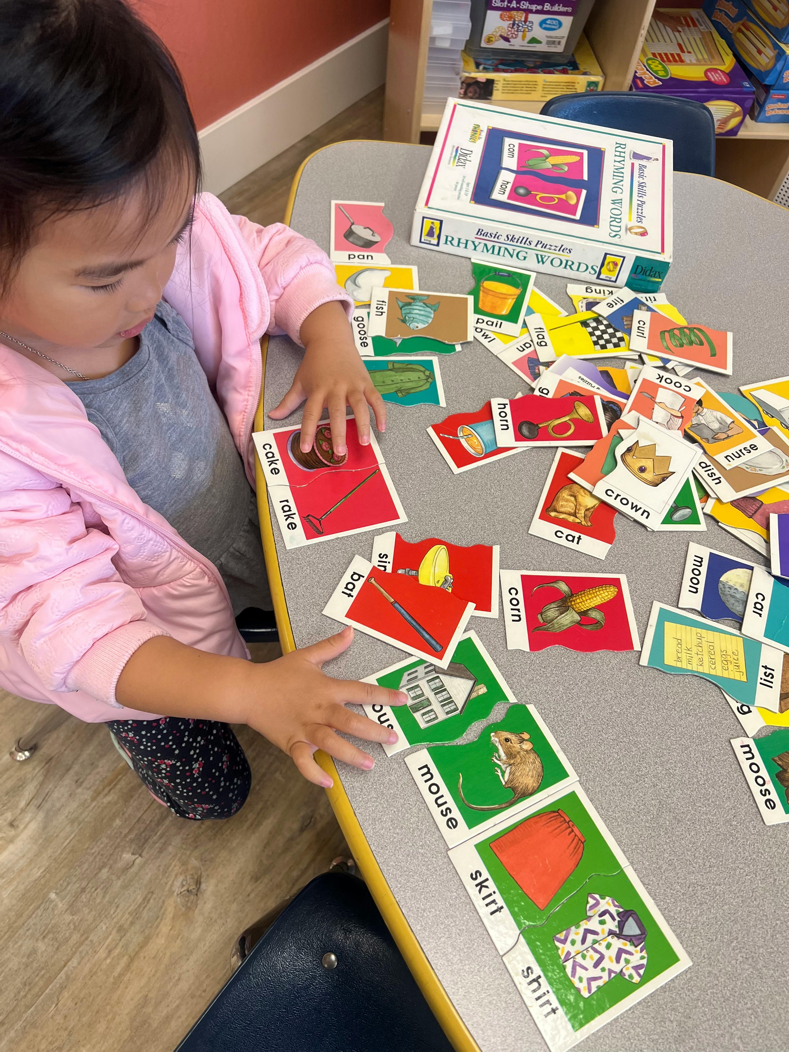 Child playing with rhyming word cards on a table