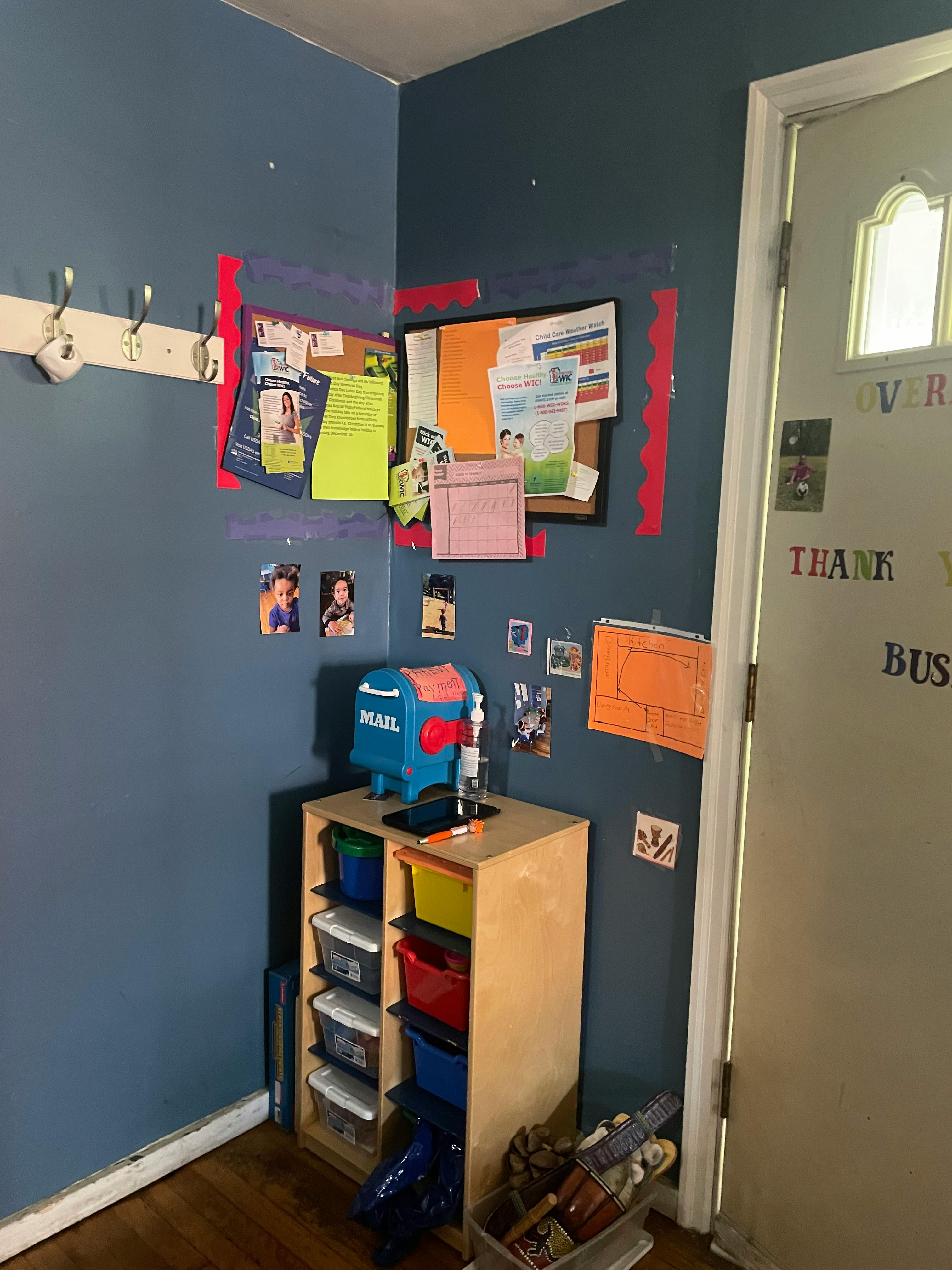 Wall with bulletin boards, coat rack, and storage unit with toy mailbox