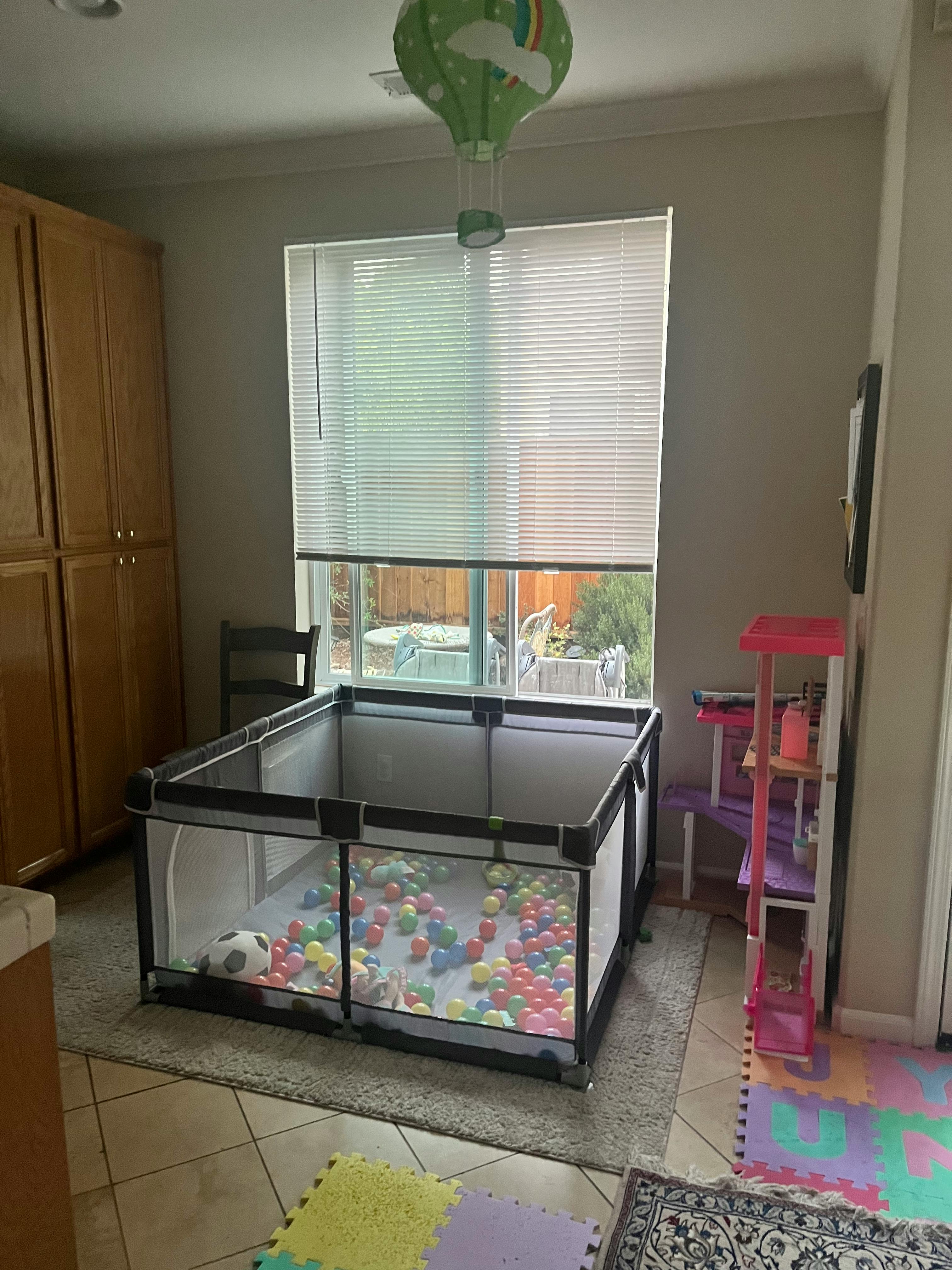 Playpen filled with colorful balls in a room with a window