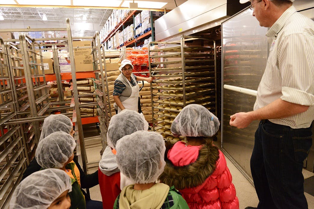 Adults and children in hairnets in a commercial kitchen