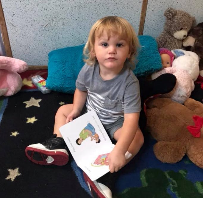 Child sitting on a rug holding an open book