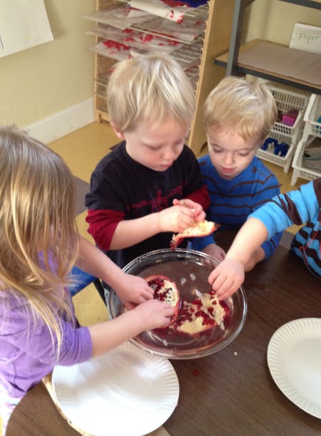 Children removing seeds from pomegranates in a bowl of water