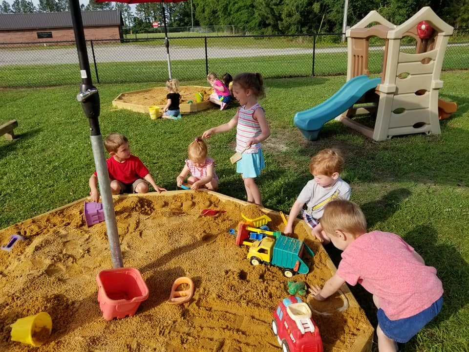 Children playing in a sandbox with toys