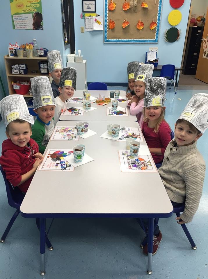 Children wearing paper chef hats sitting at a table
