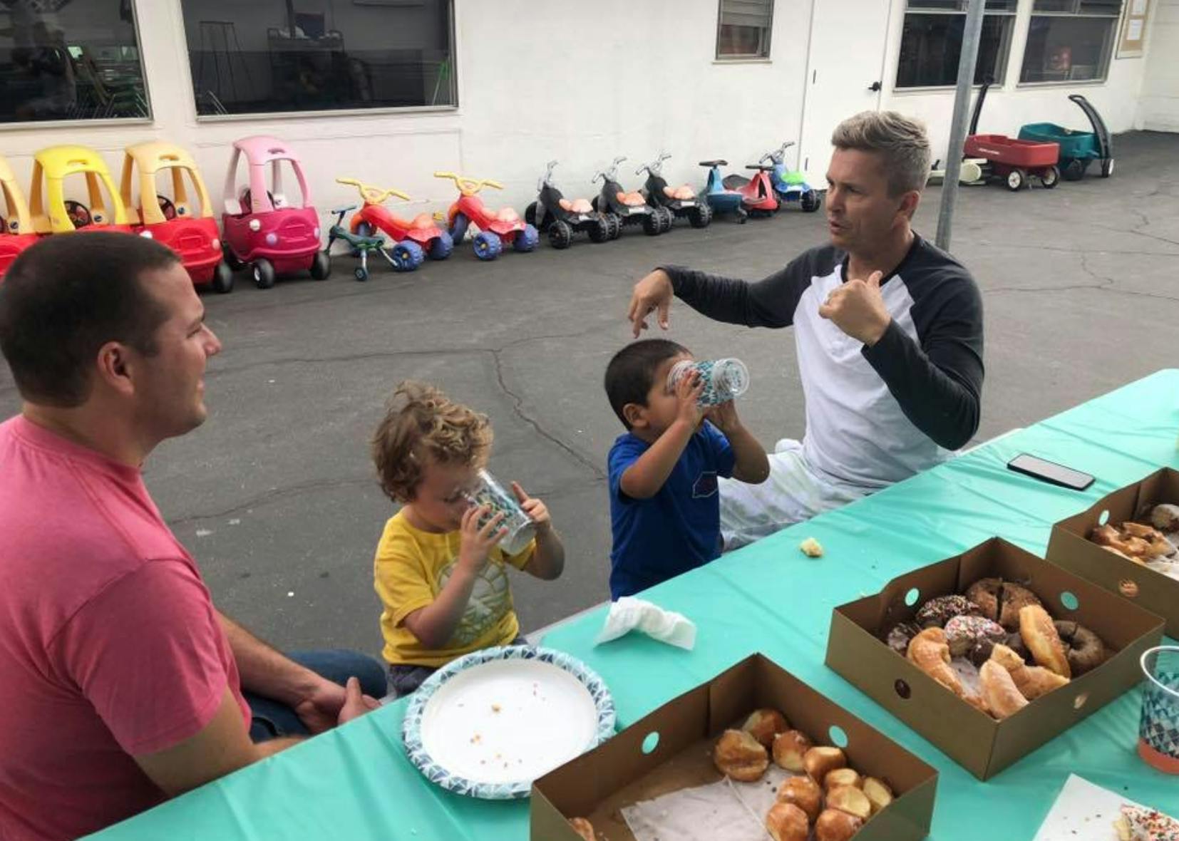 Two people and two children sitting at a table with food and drinks