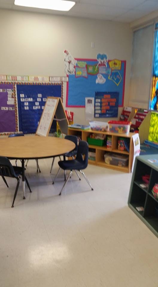 Classroom with a round table and chairs, bulletin boards, and storage shelves