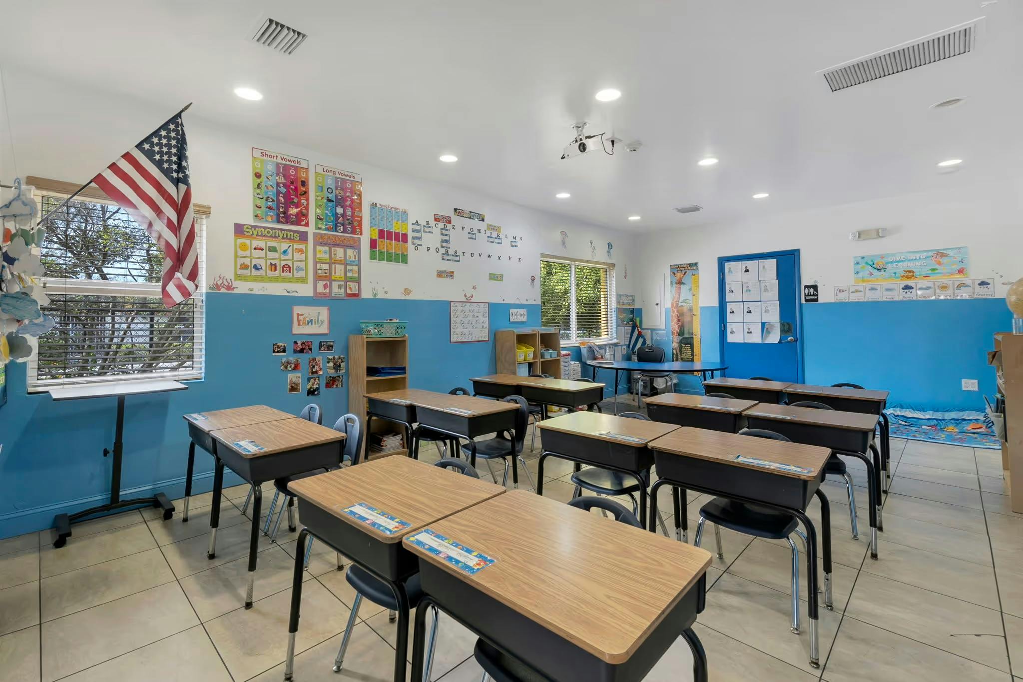 Empty classroom with rows of student desks and an American flag in the window
