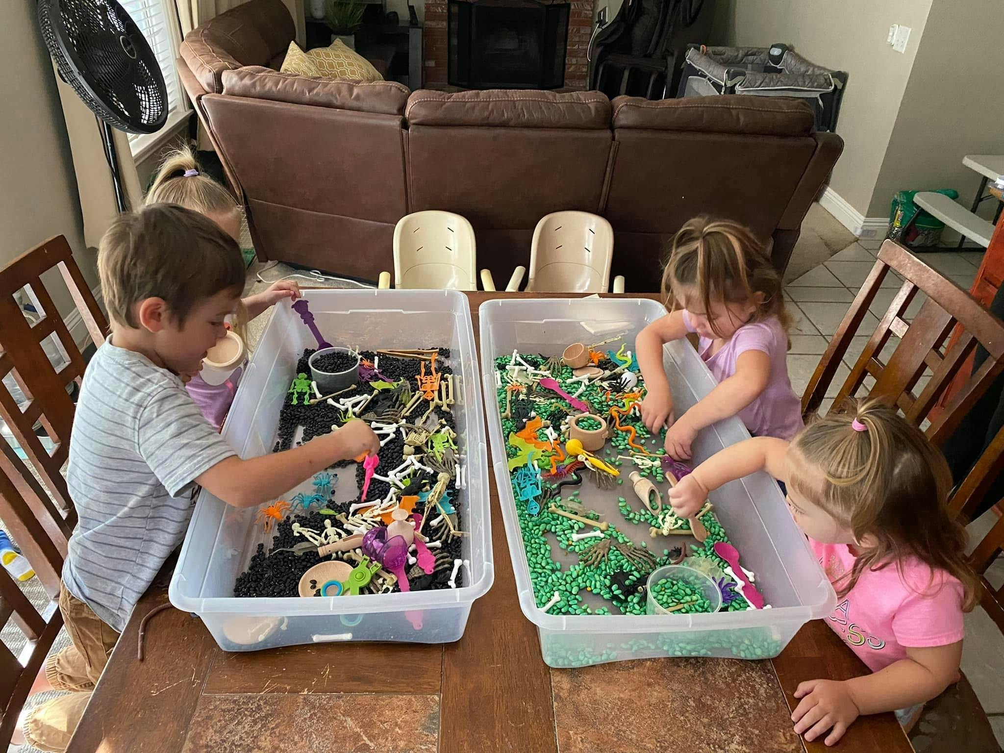 Three children playing with toys in sensory bins