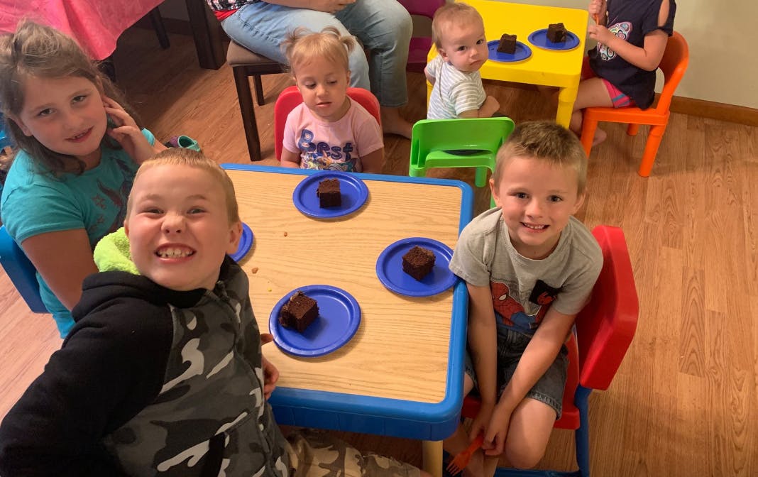 Children sitting at tables with dessert
