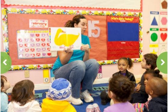 Person showing a drawing of a duck to children in a classroom