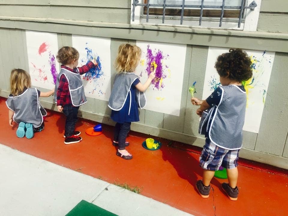 Four children painting on a wall