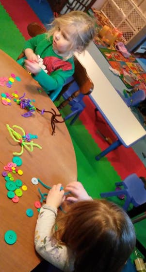 Two children playing with craft supplies at a table