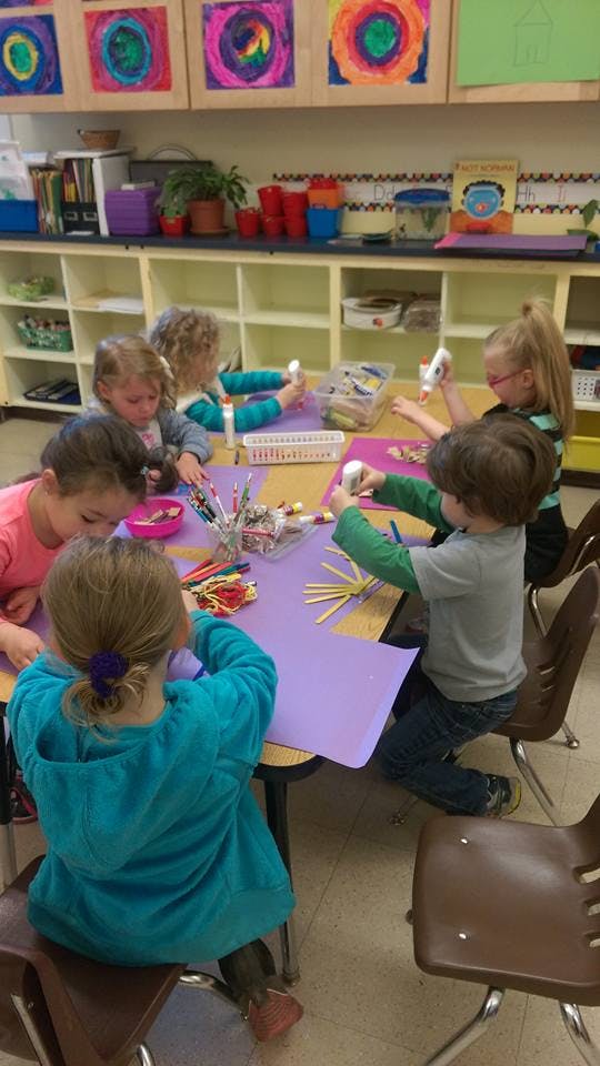 Children doing crafts at a table in a classroom