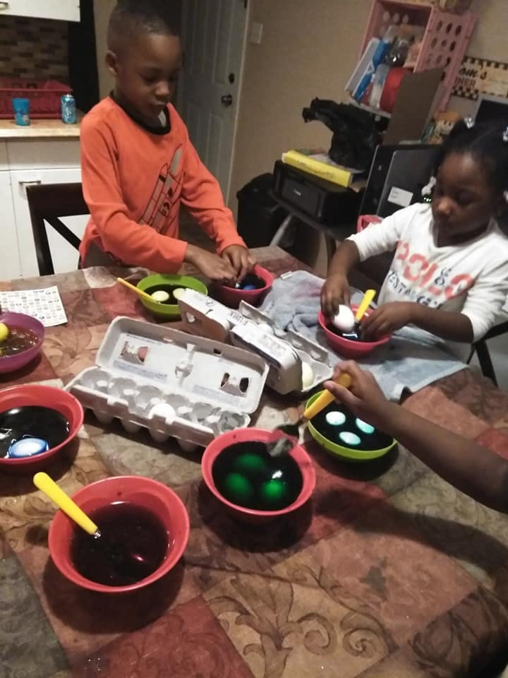 Two children dyeing eggs at a table