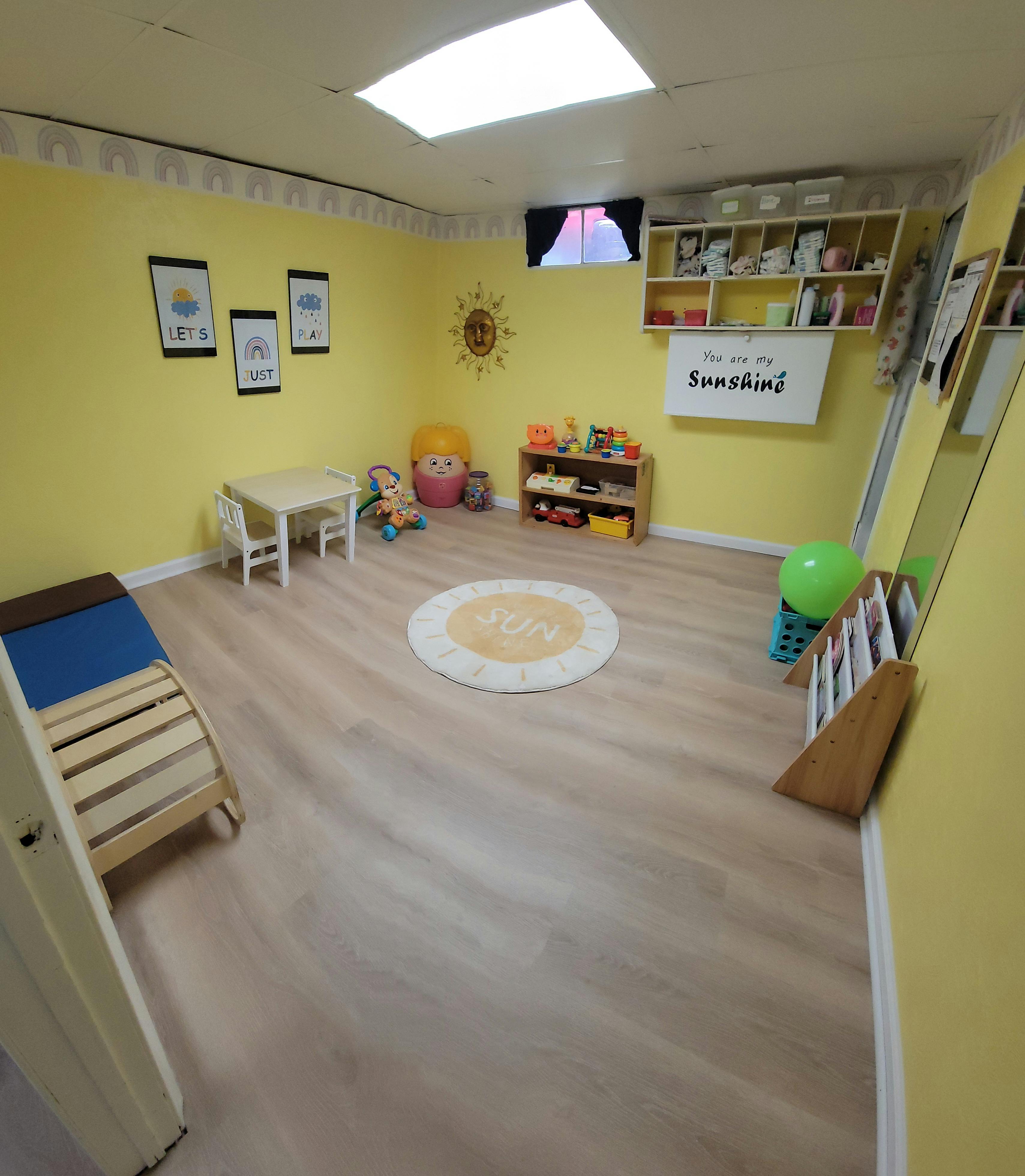 Playroom with yellow walls, small table and chairs, toys, and a rug