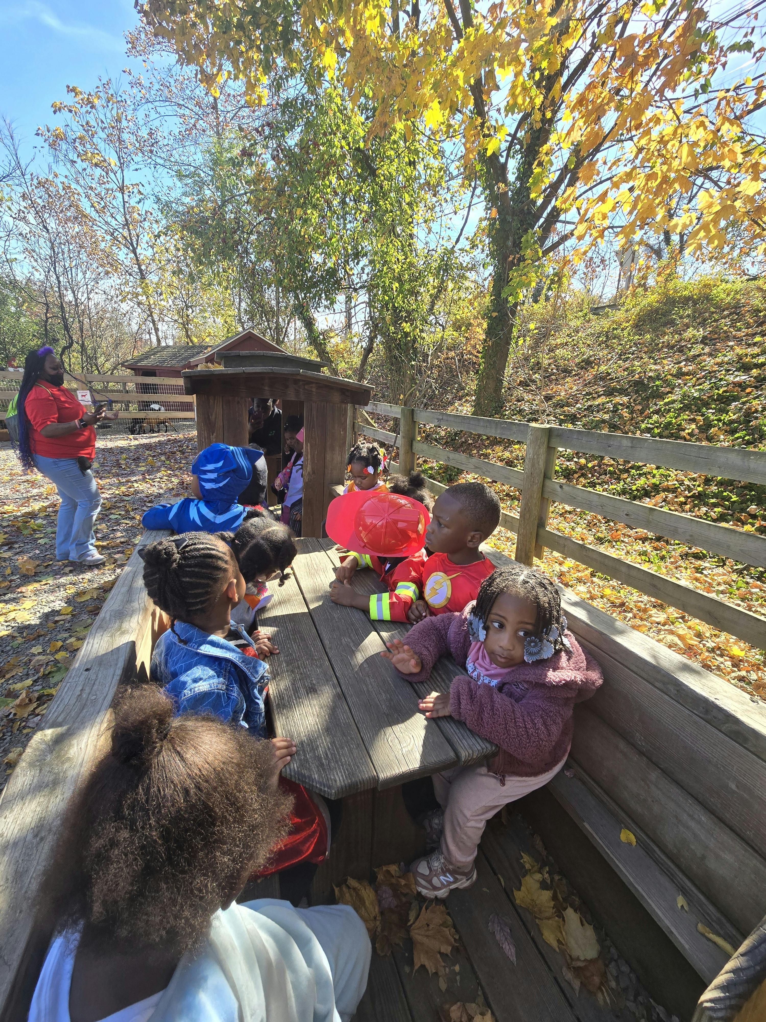 Group of children sitting at a wooden picnic table outdoors