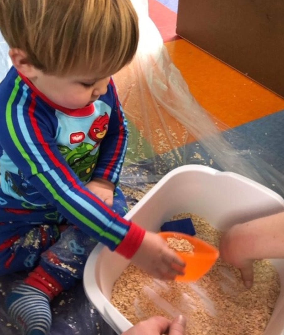 Child playing with grain in a bin