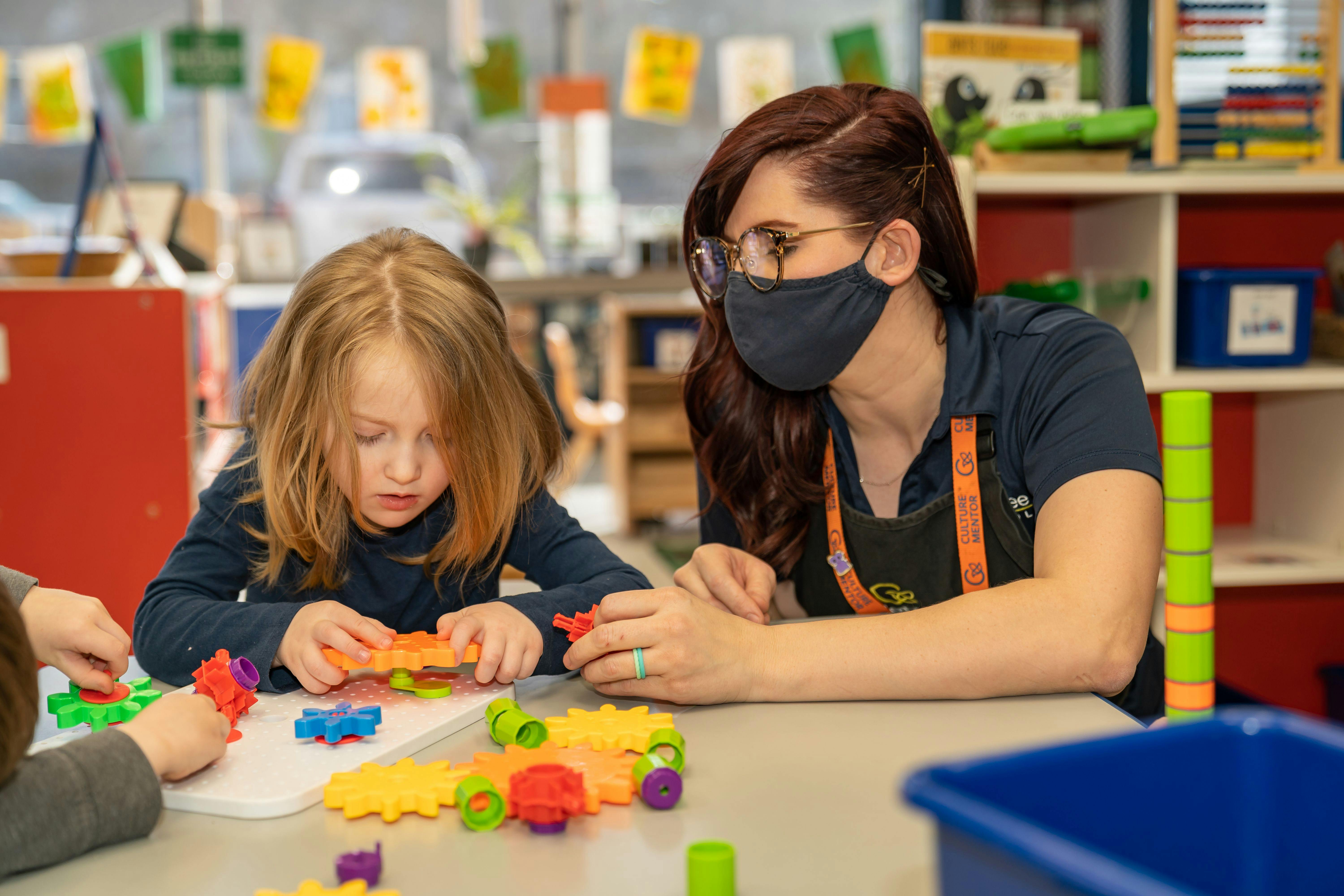 Adult and child playing with colorful building toys at a table