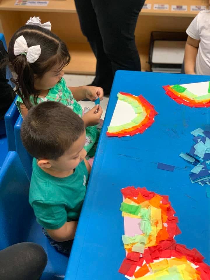 Two children at a table doing crafts with paper crafts